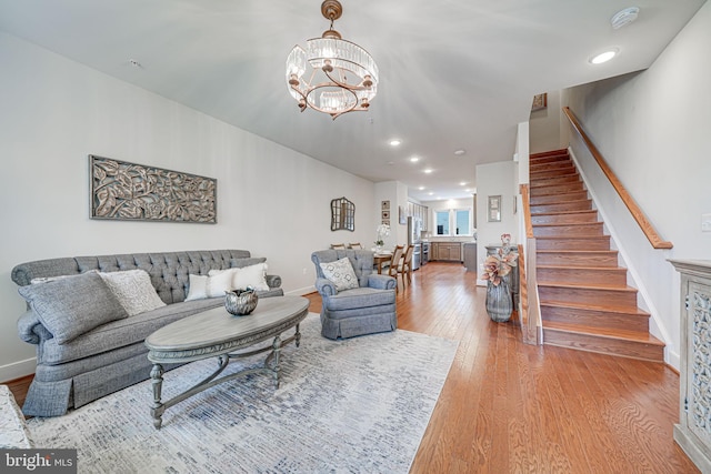 living room with an inviting chandelier, stairway, wood finished floors, and baseboards