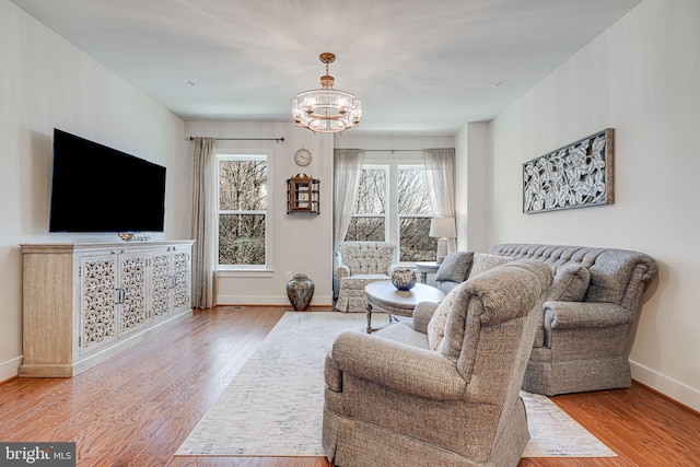 living area with an inviting chandelier, baseboards, and wood finished floors