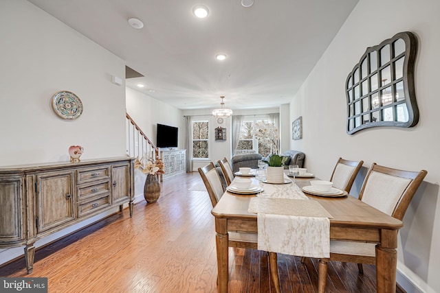 dining area with an inviting chandelier, stairway, baseboards, and light wood finished floors