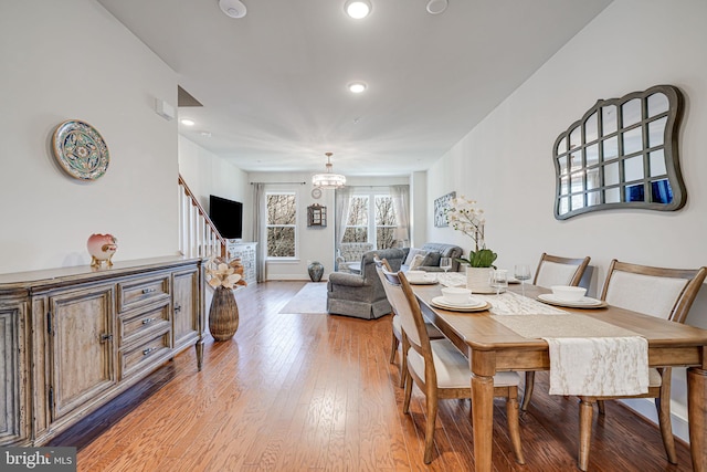 dining area with recessed lighting, an inviting chandelier, light wood-style flooring, and stairs