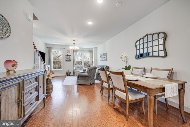 dining area with a notable chandelier, stairway, baseboards, and wood-type flooring