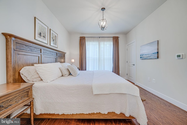 bedroom with an inviting chandelier, baseboards, and wood finished floors