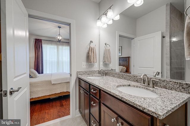 ensuite bathroom with ensuite bath, double vanity, tile patterned floors, and a sink