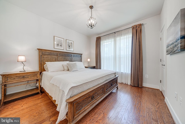 bedroom featuring baseboards, an inviting chandelier, and light wood-style flooring