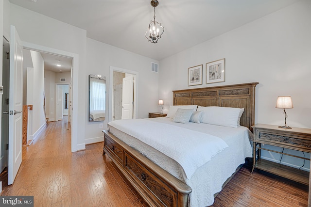 bedroom featuring visible vents, baseboards, light wood-type flooring, and an inviting chandelier