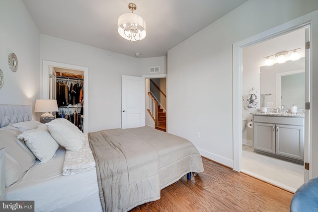 bedroom featuring visible vents, a sink, light wood-style floors, a closet, and a walk in closet