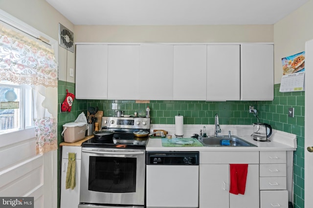 kitchen with white dishwasher, a sink, stainless steel range with electric cooktop, light countertops, and white cabinetry