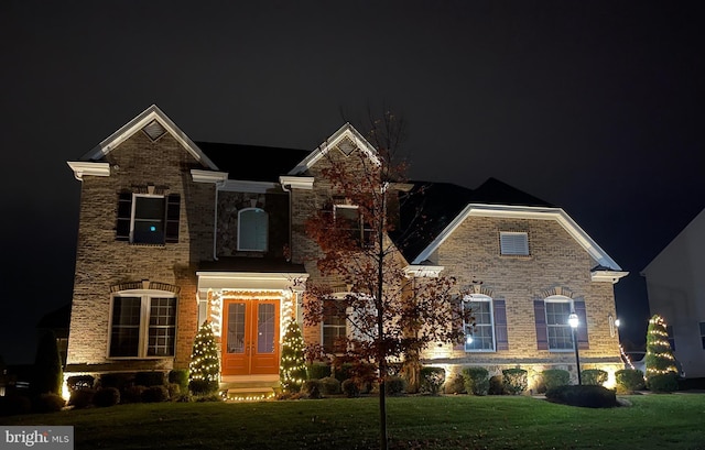 view of front of house with stone siding, french doors, and a lawn