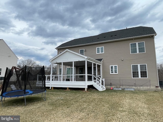 back of house featuring a trampoline and a yard