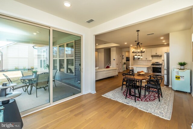 dining room featuring light wood-style flooring, recessed lighting, a notable chandelier, visible vents, and stairway