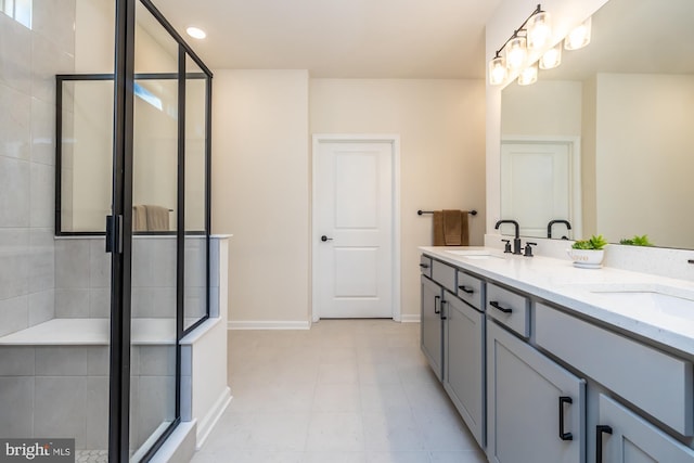 bathroom featuring double vanity, a stall shower, baseboards, and a sink