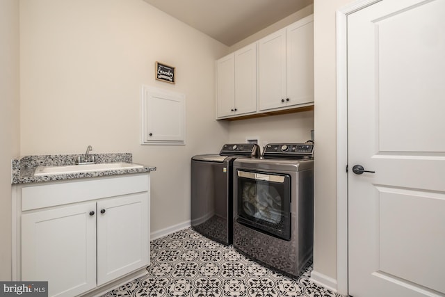 washroom with light tile patterned flooring, a sink, baseboards, washer and dryer, and cabinet space