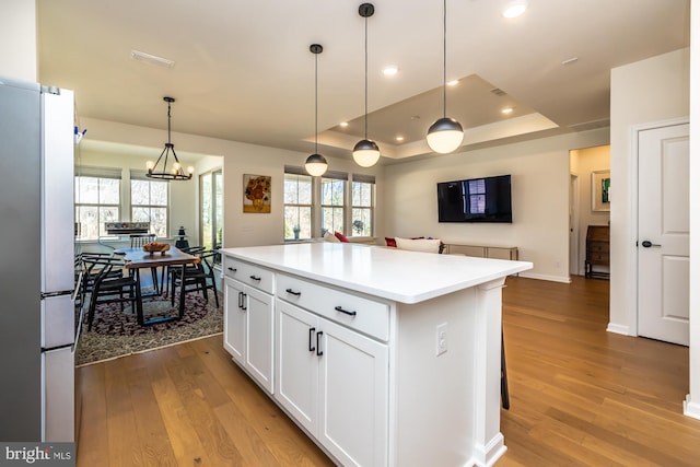 kitchen featuring recessed lighting, wood finished floors, white cabinets, freestanding refrigerator, and a tray ceiling