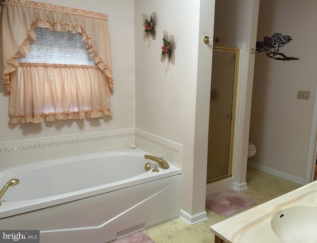 bathroom with a garden tub, toilet, a stall shower, a sink, and baseboards