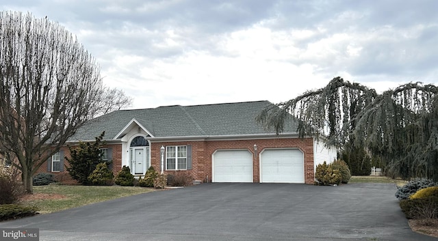 view of front of house featuring brick siding, driveway, an attached garage, and roof with shingles