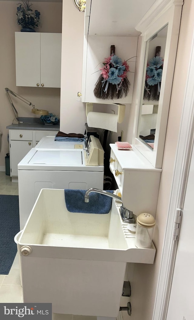 laundry area with light tile patterned floors, independent washer and dryer, and cabinet space