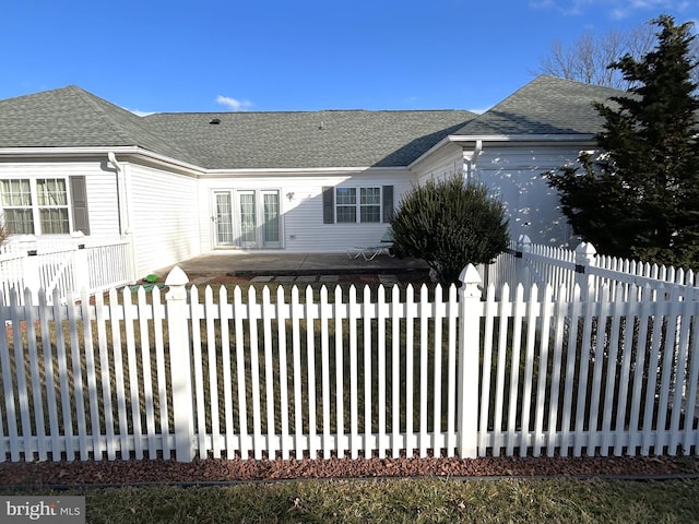 exterior space featuring roof with shingles and fence