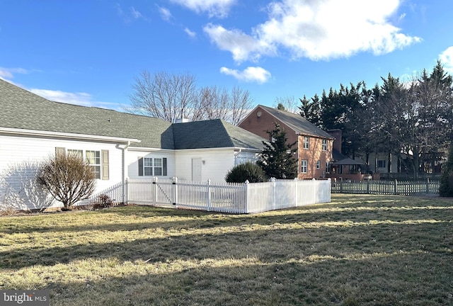 view of side of home featuring a lawn and fence