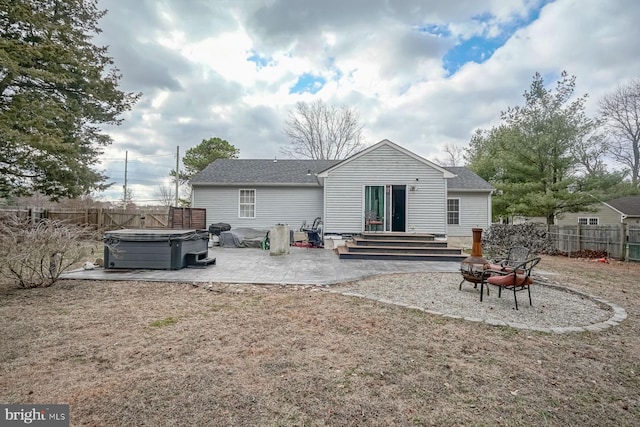 back of property featuring a patio, fence private yard, a fire pit, a shingled roof, and a hot tub