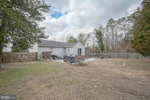 rear view of property with a lawn, a patio area, a fenced backyard, and a gate