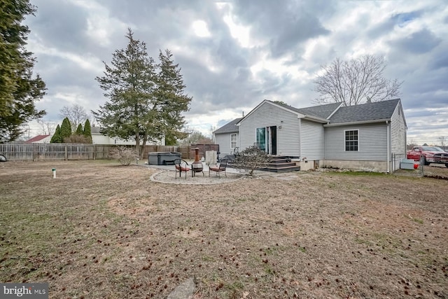 rear view of property featuring a fenced backyard, a fire pit, roof with shingles, a patio area, and a hot tub