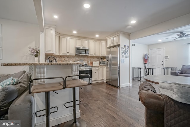 kitchen featuring recessed lighting, open floor plan, appliances with stainless steel finishes, decorative backsplash, and dark wood finished floors