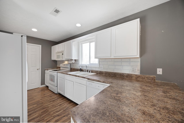 kitchen featuring dark countertops, visible vents, backsplash, a sink, and white appliances