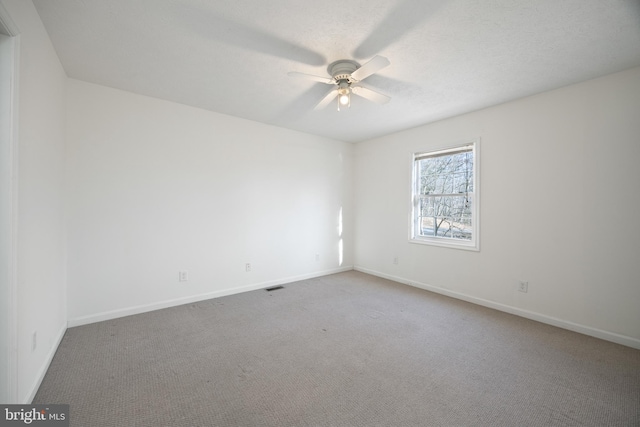 carpeted empty room featuring ceiling fan, a textured ceiling, visible vents, and baseboards