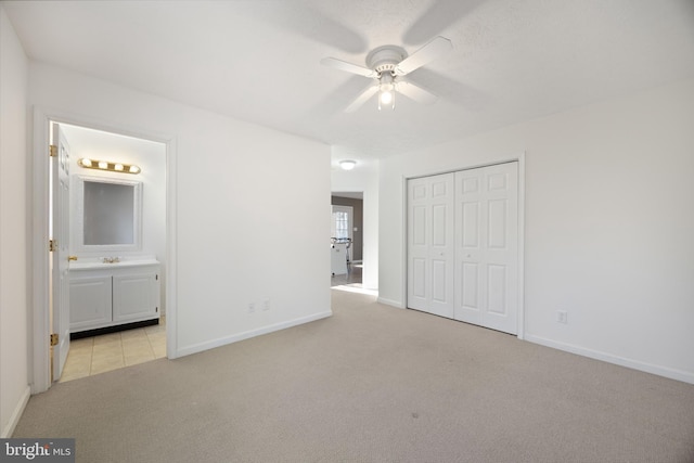 unfurnished bedroom with a closet, light colored carpet, connected bathroom, ceiling fan, and baseboards