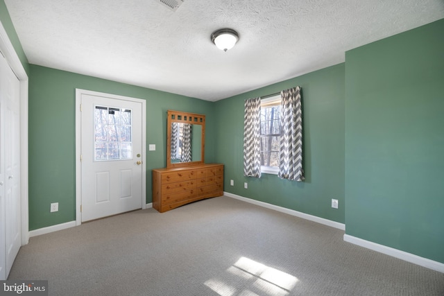 interior space featuring carpet floors, a textured ceiling, and baseboards