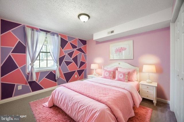 carpeted bedroom featuring visible vents, an accent wall, baseboards, and a textured ceiling