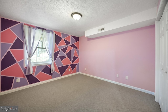 carpeted spare room with wallpapered walls, an accent wall, baseboards, and a textured ceiling