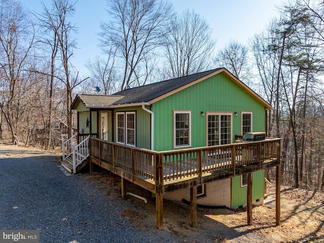 view of front of house featuring roof with shingles, driveway, and a deck