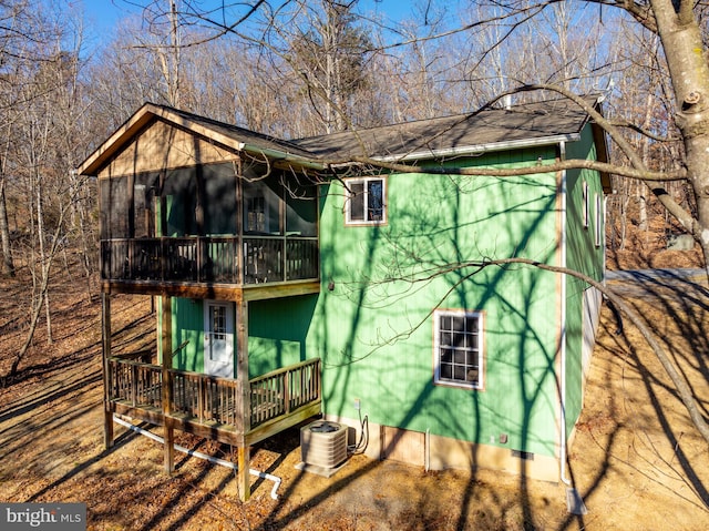 view of home's exterior featuring cooling unit, a sunroom, and a wooden deck