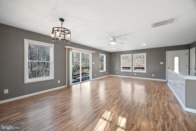 unfurnished living room with wood finished floors, visible vents, and baseboards