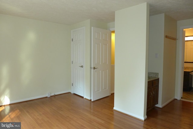 interior space featuring light wood-type flooring, a textured ceiling, and baseboards