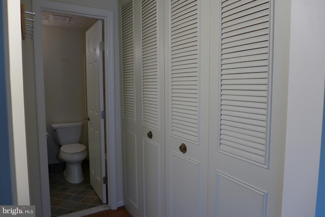 bathroom with toilet, tile patterned flooring, visible vents, and a closet