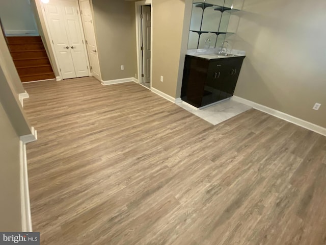 unfurnished living room with stairs, baseboards, and wood finished floors