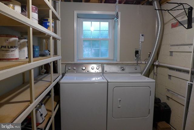 laundry room featuring laundry area, separate washer and dryer, and concrete block wall