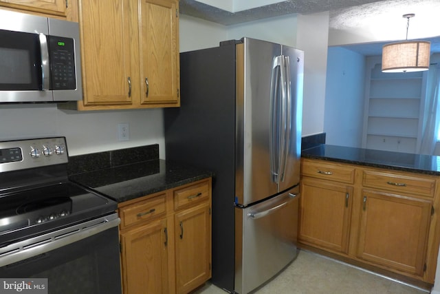 kitchen with appliances with stainless steel finishes, brown cabinetry, and dark stone countertops