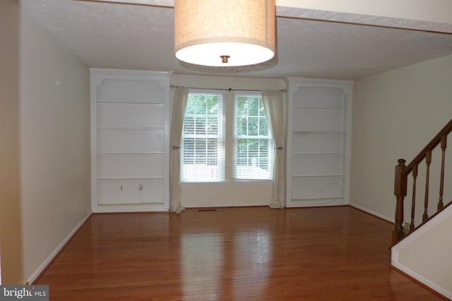 entryway featuring stairs, a textured ceiling, baseboards, and wood finished floors