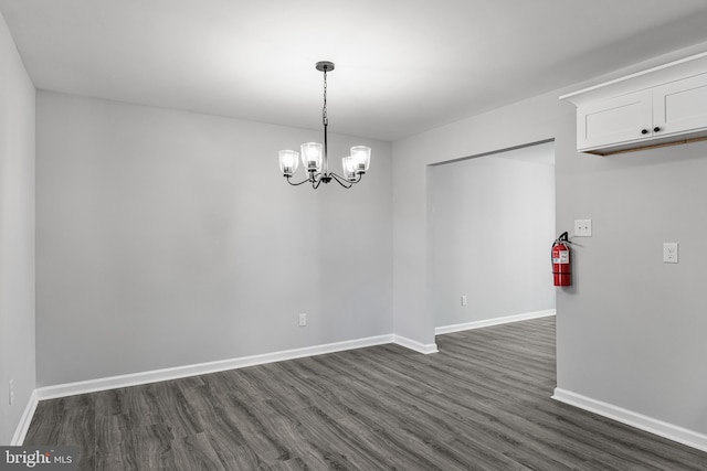 unfurnished dining area with dark wood-style floors, baseboards, and a chandelier