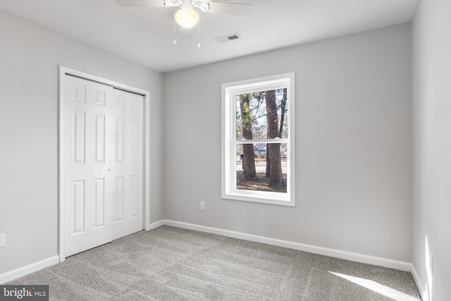 unfurnished bedroom featuring carpet, a closet, visible vents, a ceiling fan, and baseboards