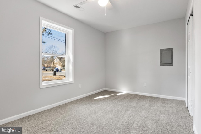 carpeted spare room featuring electric panel, ceiling fan, visible vents, and baseboards