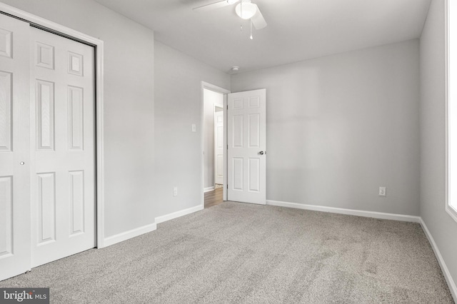 unfurnished bedroom with a closet, carpet flooring, a ceiling fan, and baseboards