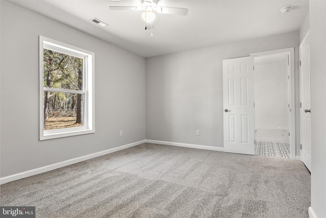 empty room with carpet floors, baseboards, visible vents, and ceiling fan