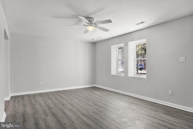 unfurnished room with a ceiling fan, baseboards, visible vents, and dark wood-type flooring