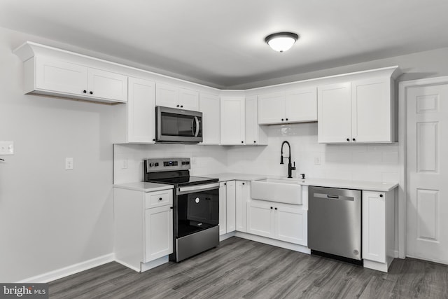 kitchen featuring dark wood finished floors, light countertops, appliances with stainless steel finishes, white cabinets, and a sink