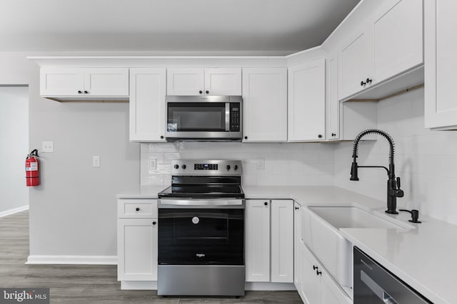 kitchen featuring white cabinetry, stainless steel appliances, decorative backsplash, and light countertops