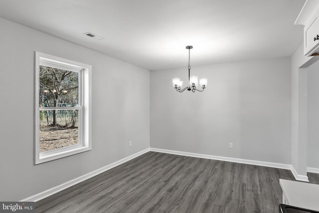 interior space featuring a notable chandelier, dark wood-type flooring, visible vents, and baseboards